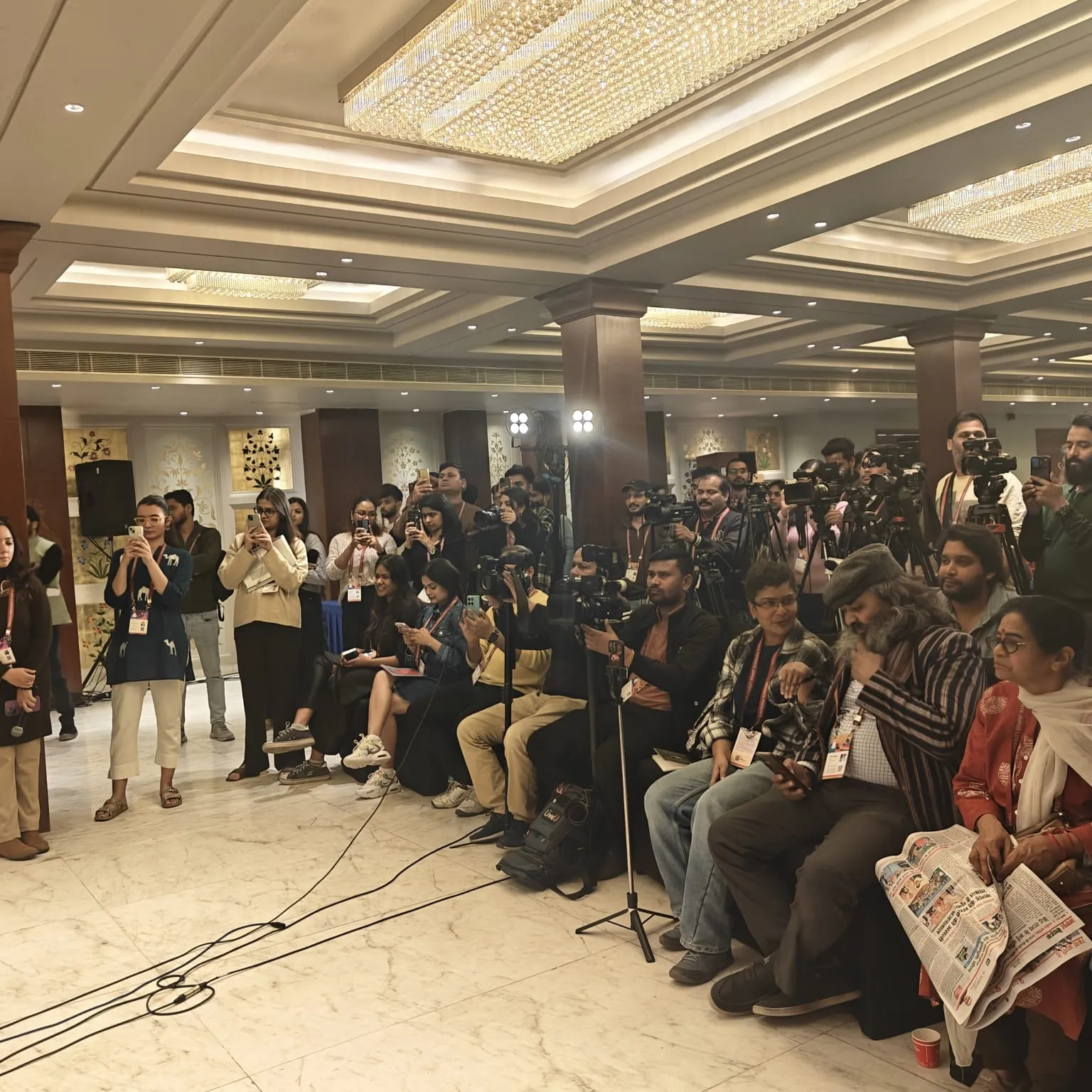A crowded press conference with dozens of photographers, television crews and reporters filling the room.