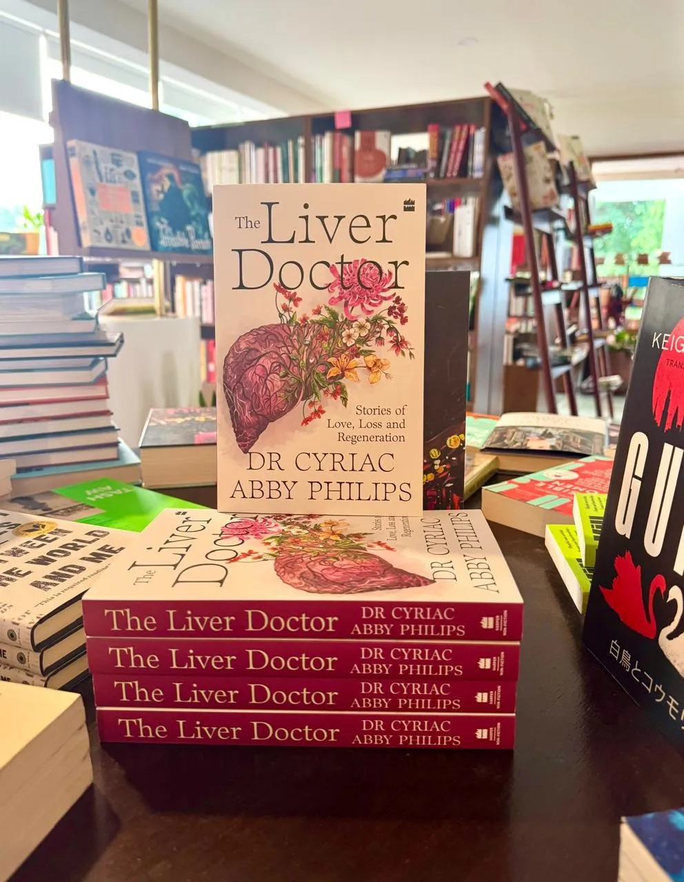 Copies of The Liver Doctor by Dr Cyriac Abby Philips displayed face-out and stacked on a bookshop table.